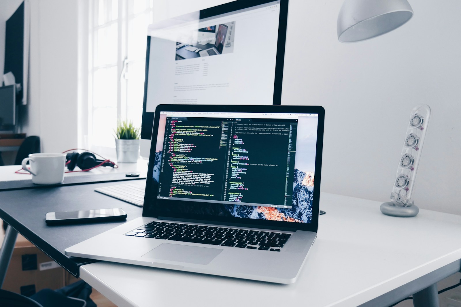 Software development workspace with code on a laptop
